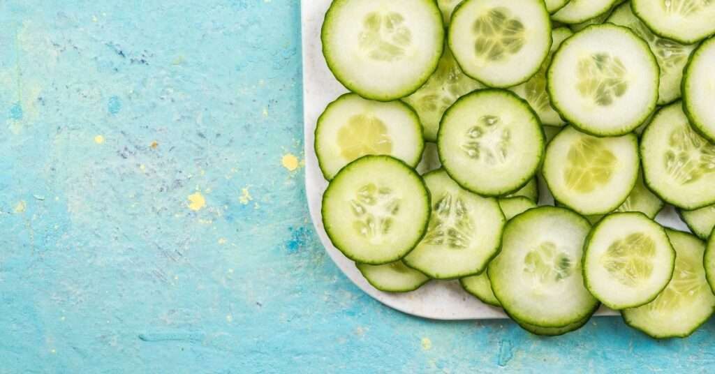 Sliced cucumbers on a marble board against a blue textured background