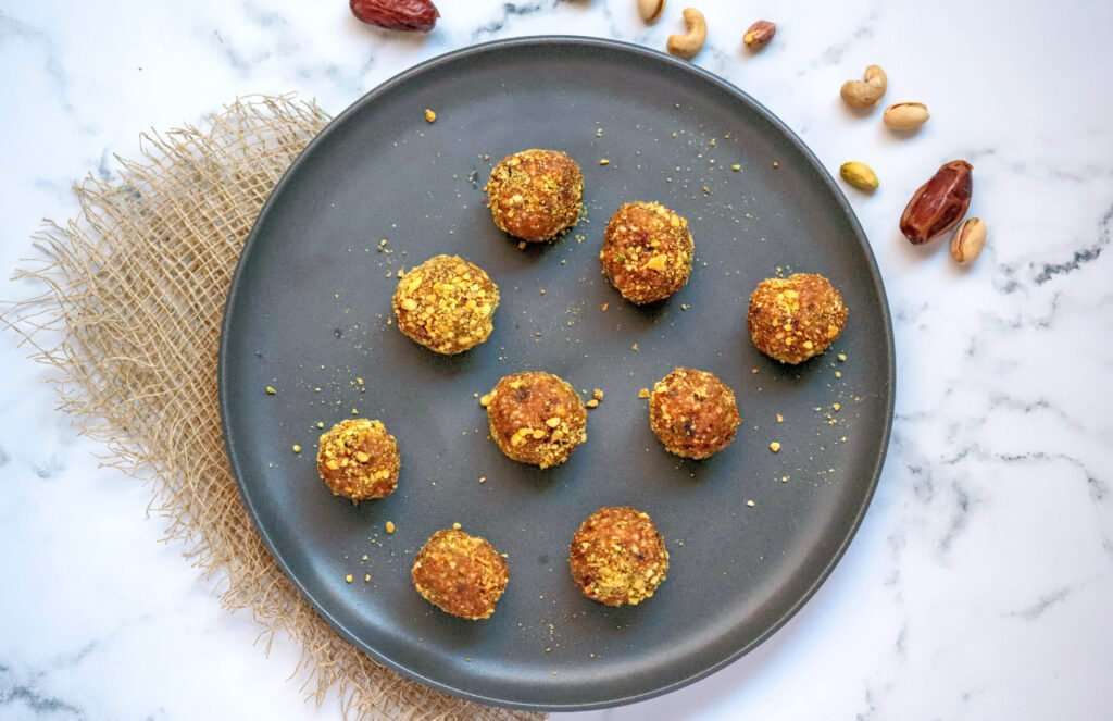 pumpkin pistachio date balls grouped together on a navy blue plate from the top